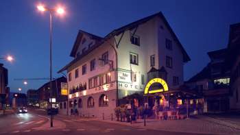 Vista esterna del ristorante Adler di sera, con facciata tradizionale e illuminazione d'atmosfera Vista esterna del ristorante Adler di sera, con facciata tradizionale e illuminazione d'atmosfera