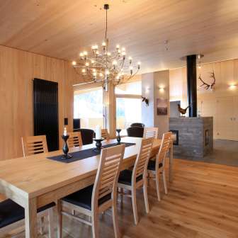 Interni in legno chiaro con tavolo da pranzo e caminetto presso la Haus Ochsenkopf a Malbun, Liechtenstein
