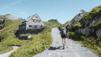 Escursionista con zaino in spalla lungo un sentiero di montagna verso il rifugio Pfälzerhütte nelle Alpi del Liechtenstein